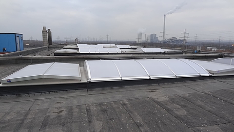 Multiple Lichtband B units by roda on an industrial flat roof under a cloudy sky.