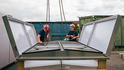 Doppelklappe Phönix von roda bei einer Sanierung Arbeiter installieren ein Belüftungssystem auf dem Dach mit Schutzgittern unter Verwendung von Ketten
