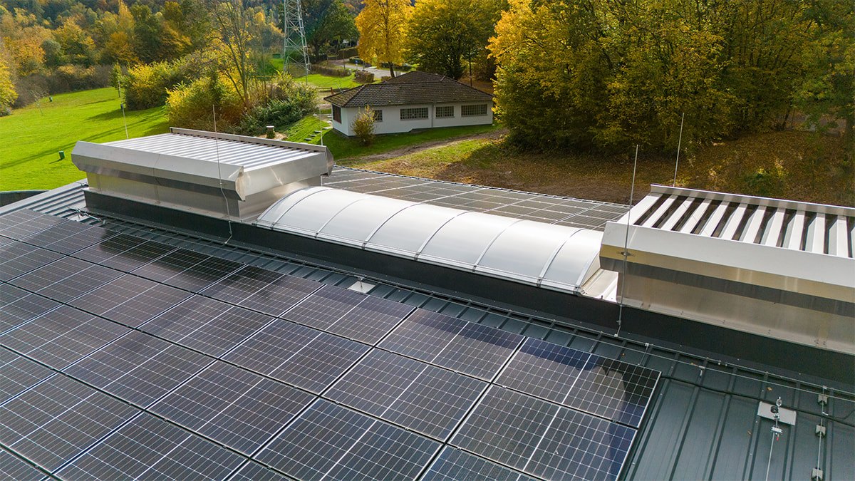 Lichtbänder auf dem Industriedach der Kläranlage Scheid Am See und herbstlicher Landschaft im Hintergrund.