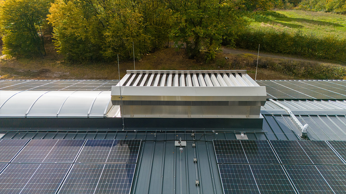 Nahaufnahme eines Industriedachs mit Solarpaneelen und einem Dachlüfter.